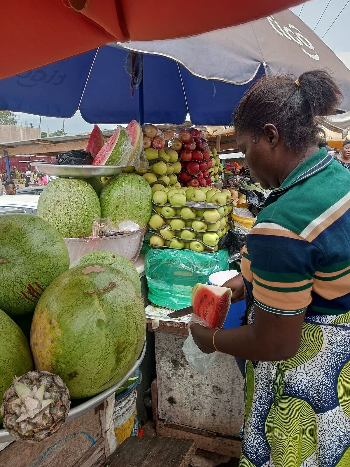 A fruit seller serves a slice of watermelon at her stall in Ajumako, Ghana.